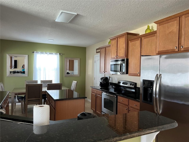 kitchen with stainless steel appliances, a textured ceiling, and a kitchen island