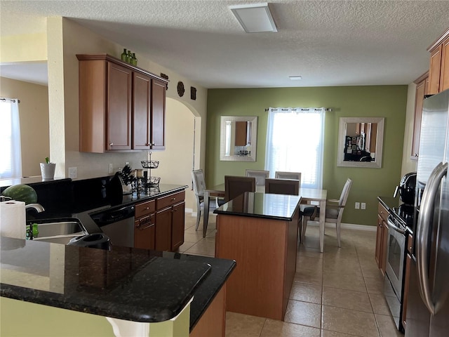 kitchen with appliances with stainless steel finishes, a textured ceiling, a center island, and sink