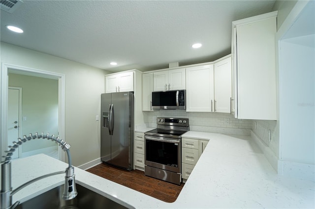 kitchen featuring white cabinetry, backsplash, dark hardwood / wood-style flooring, stainless steel appliances, and sink