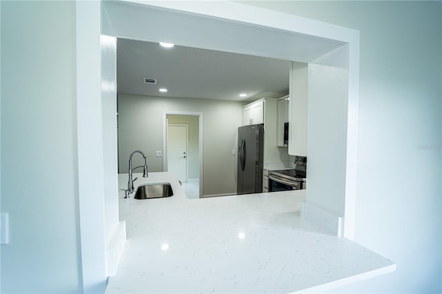 kitchen featuring light stone counters, sink, white cabinets, kitchen peninsula, and appliances with stainless steel finishes