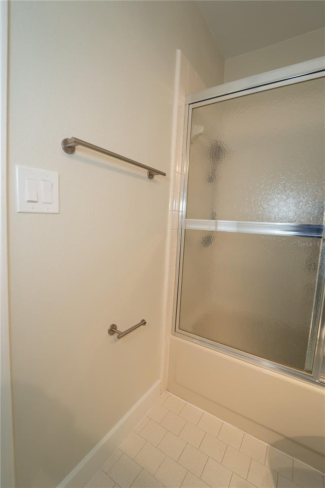 bathroom featuring bath / shower combo with glass door and tile patterned flooring