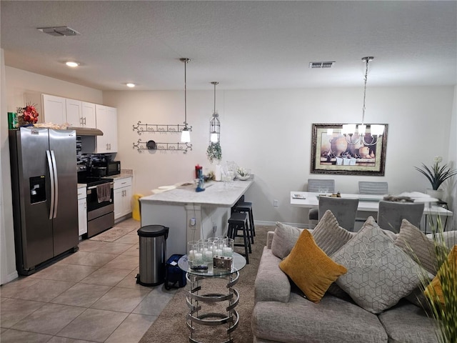 kitchen featuring white cabinets, appliances with stainless steel finishes, hanging light fixtures, and a kitchen bar