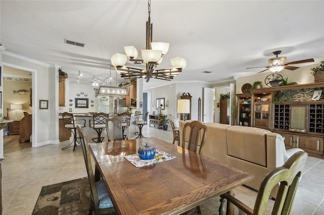 tiled dining room with ceiling fan with notable chandelier and crown molding