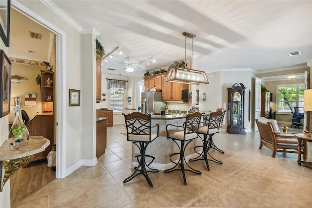 dining area with ceiling fan, crown molding, and light tile patterned floors