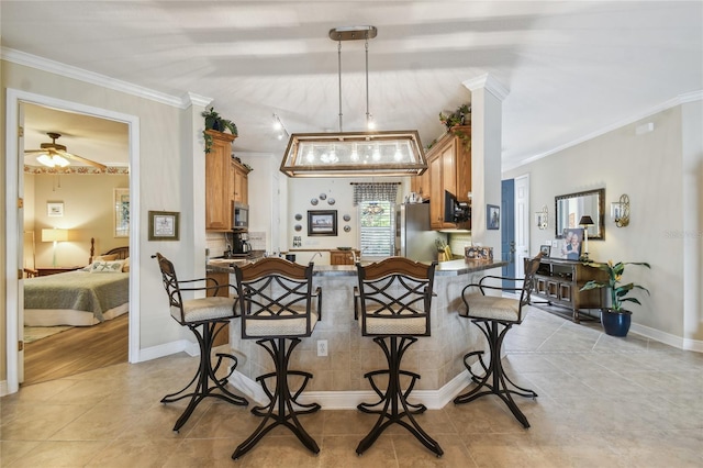 tiled dining room with ceiling fan and ornamental molding