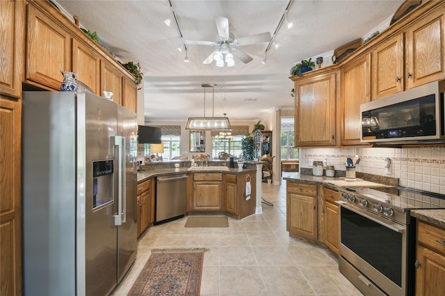 kitchen featuring a wealth of natural light, ceiling fan, appliances with stainless steel finishes, and hanging light fixtures