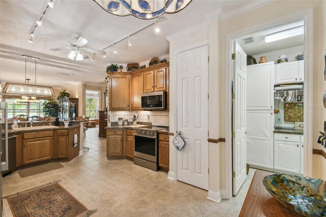 kitchen featuring ceiling fan with notable chandelier, backsplash, appliances with stainless steel finishes, decorative light fixtures, and crown molding