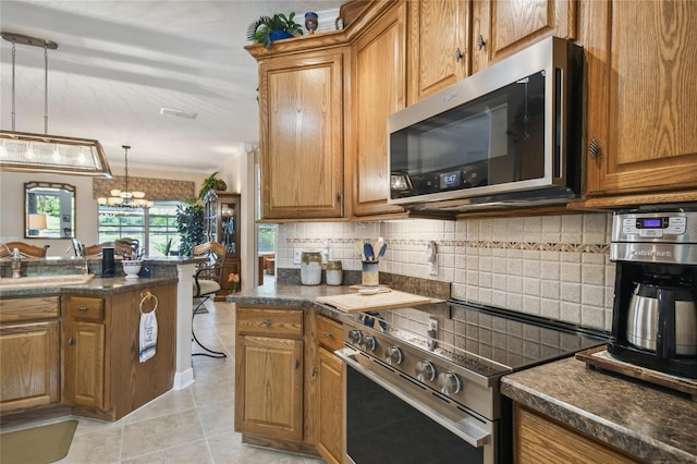 kitchen featuring appliances with stainless steel finishes, light tile patterned flooring, backsplash, pendant lighting, and a notable chandelier