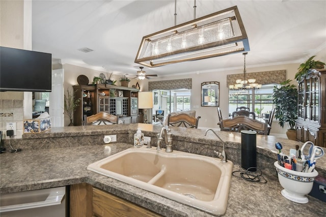 kitchen with ornamental molding, dishwasher, ceiling fan with notable chandelier, and sink