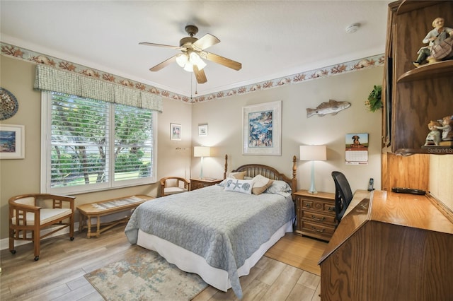 bedroom featuring light wood-type flooring, ornamental molding, and ceiling fan