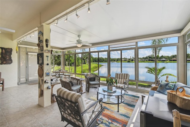 sunroom featuring a water view, ceiling fan, a healthy amount of sunlight, and rail lighting