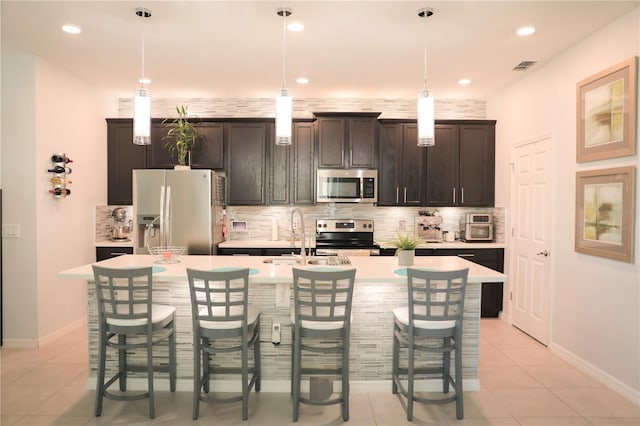 kitchen featuring an island with sink, dark brown cabinets, and stainless steel appliances