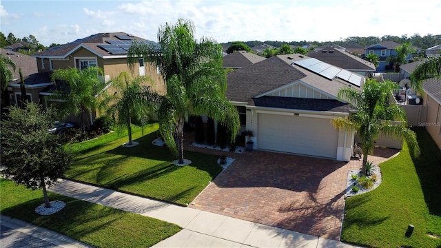 view of front facade featuring solar panels, a front yard, and a garage