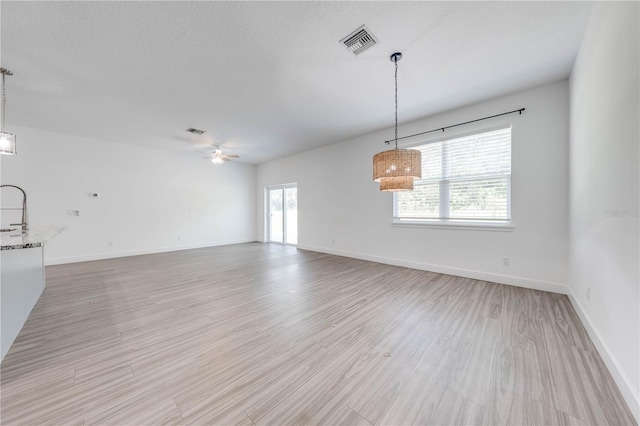 interior space with ceiling fan, a textured ceiling, and light wood-type flooring