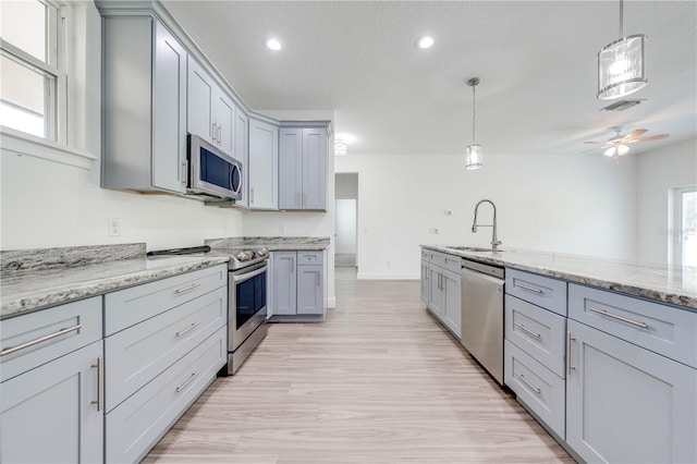 kitchen with gray cabinetry, stainless steel appliances, sink, pendant lighting, and a textured ceiling