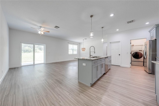 kitchen with light hardwood / wood-style flooring, gray cabinetry, sink, appliances with stainless steel finishes, and washing machine and clothes dryer