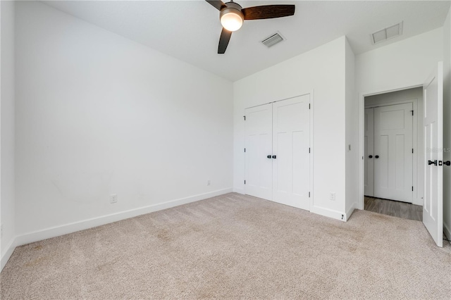 unfurnished bedroom with a closet, ceiling fan, and light carpet