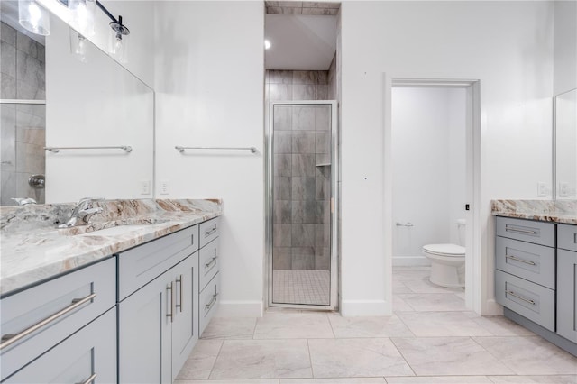 bathroom featuring toilet, vanity, and a shower with door