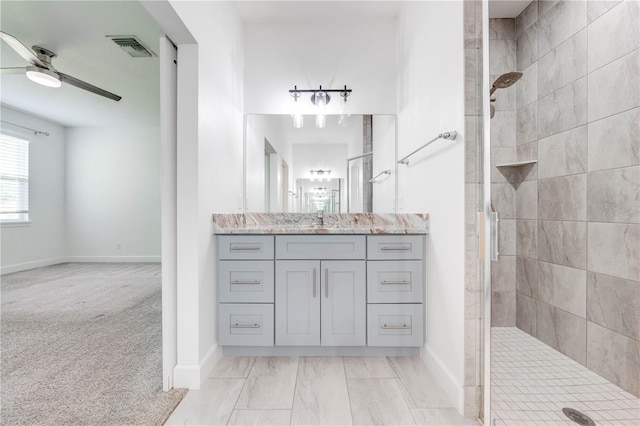 bathroom with vanity, a tile shower, and ceiling fan