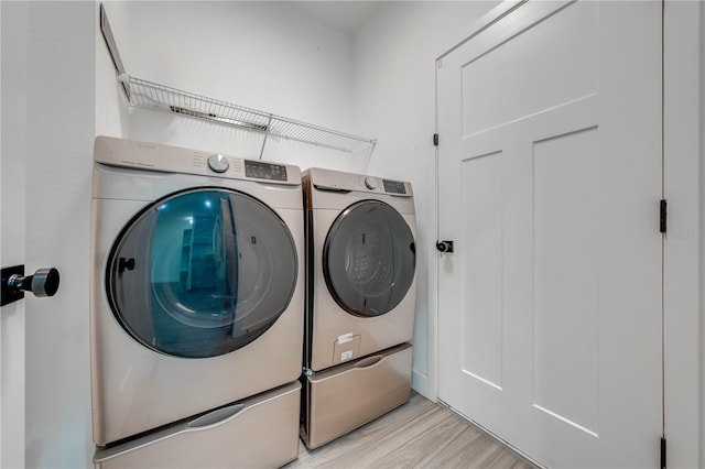 laundry area with washer and clothes dryer and light wood-type flooring