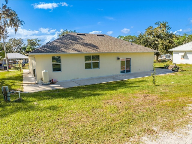 back of house with a yard, stucco siding, a patio, and roof with shingles