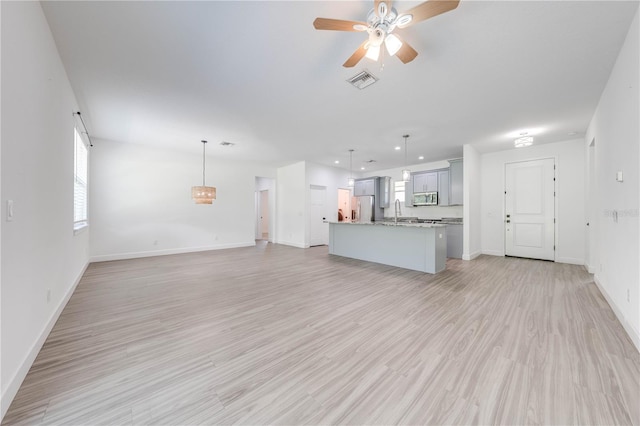 unfurnished living room featuring light hardwood / wood-style floors, sink, and ceiling fan