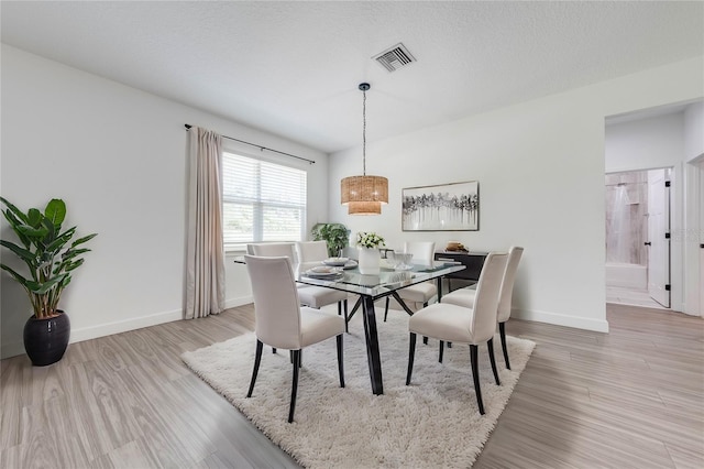 dining room featuring light hardwood / wood-style floors and a textured ceiling