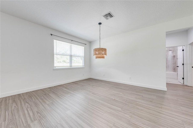 empty room with light hardwood / wood-style floors and a textured ceiling