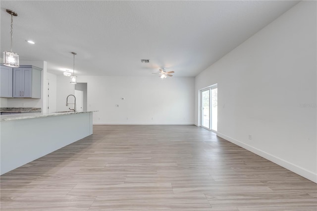 unfurnished living room with ceiling fan and sink