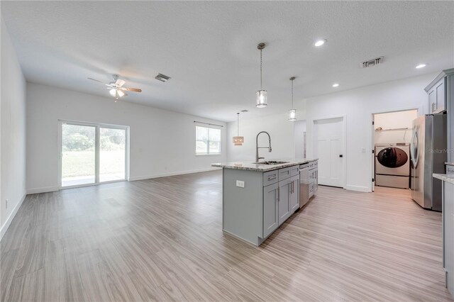 kitchen featuring visible vents, washing machine and clothes dryer, gray cabinets, stainless steel appliances, and a sink