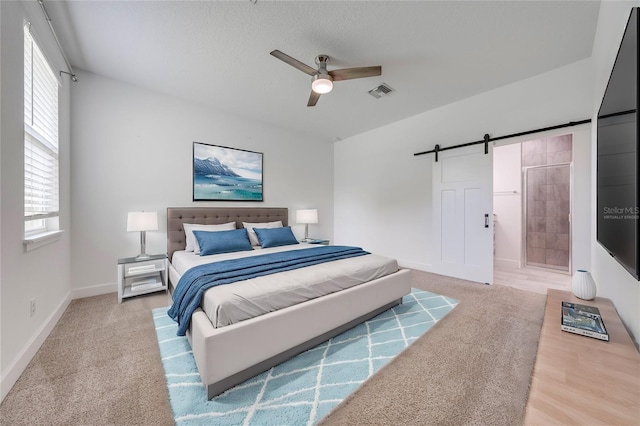 bedroom with visible vents, baseboards, a barn door, carpet floors, and a ceiling fan