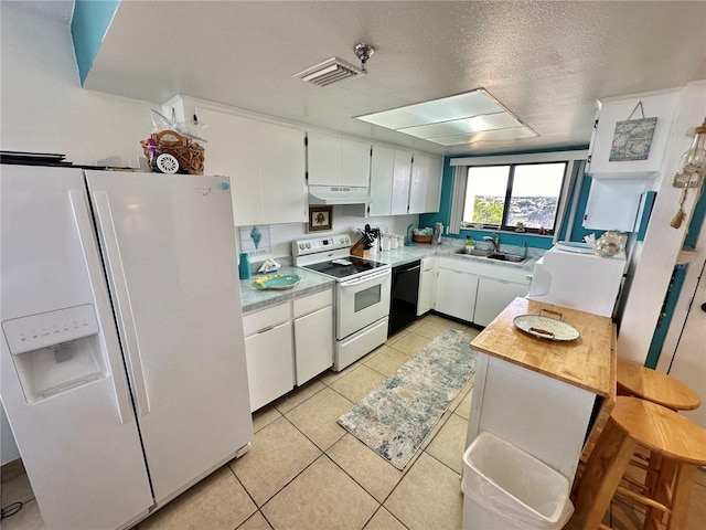 kitchen featuring white cabinets, light tile patterned flooring, sink, white appliances, and a textured ceiling