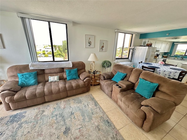 living room featuring a textured ceiling, sink, and light tile patterned floors