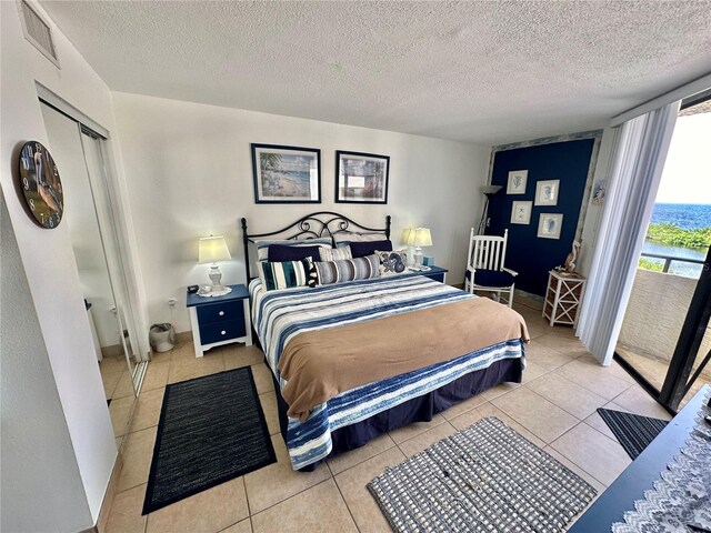 bedroom featuring a textured ceiling, light tile patterned floors, and a closet