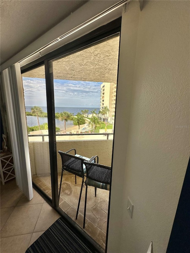 interior space with a textured ceiling, a water view, and light tile patterned flooring