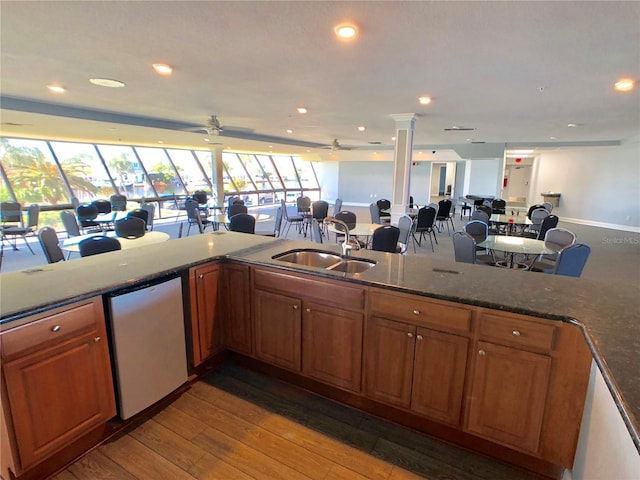 kitchen with dishwasher, ceiling fan, decorative columns, hardwood / wood-style floors, and sink