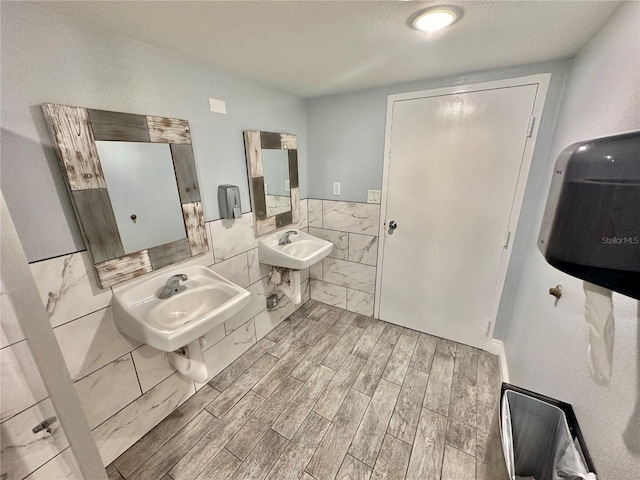 bathroom featuring sink, tile walls, hardwood / wood-style floors, and a textured ceiling