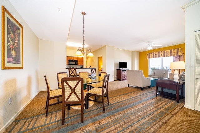 dining area with ceiling fan with notable chandelier, dark colored carpet, and ornamental molding