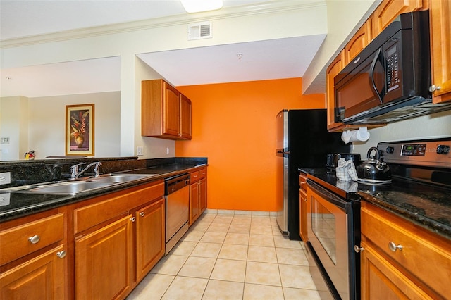 kitchen with appliances with stainless steel finishes, light tile patterned floors, dark stone counters, ornamental molding, and sink