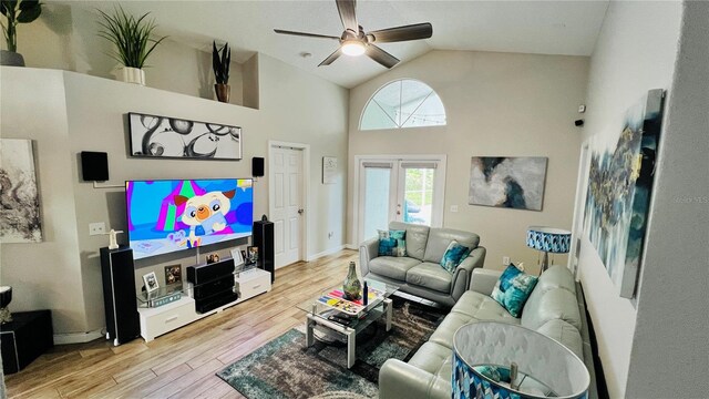 living room with light wood-type flooring, ceiling fan, french doors, and high vaulted ceiling