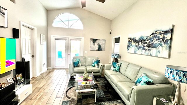 living room with ceiling fan, light wood-type flooring, french doors, and high vaulted ceiling