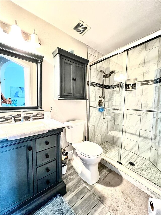 bathroom with wood-type flooring, an enclosed shower, vanity, and toilet