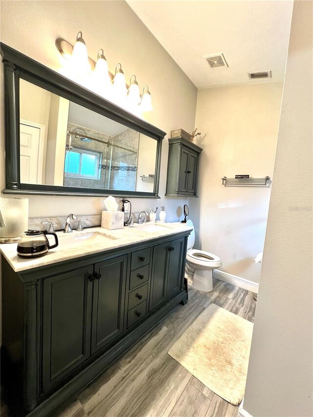 bathroom featuring wood-type flooring, vanity, toilet, and a shower with door