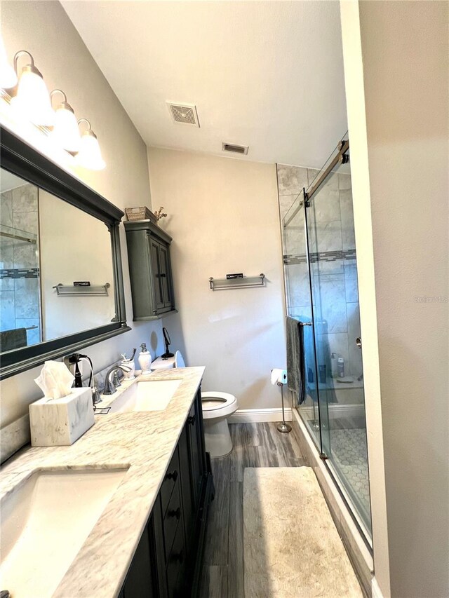 bathroom featuring walk in shower, wood-type flooring, vanity, and toilet