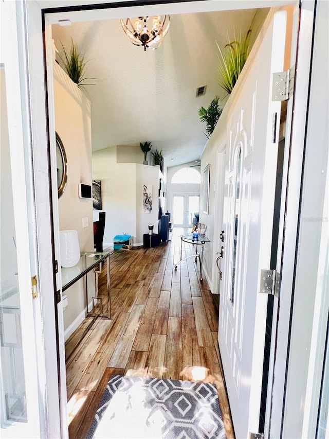 hallway featuring visible vents, baseboards, arched walkways, and hardwood / wood-style flooring
