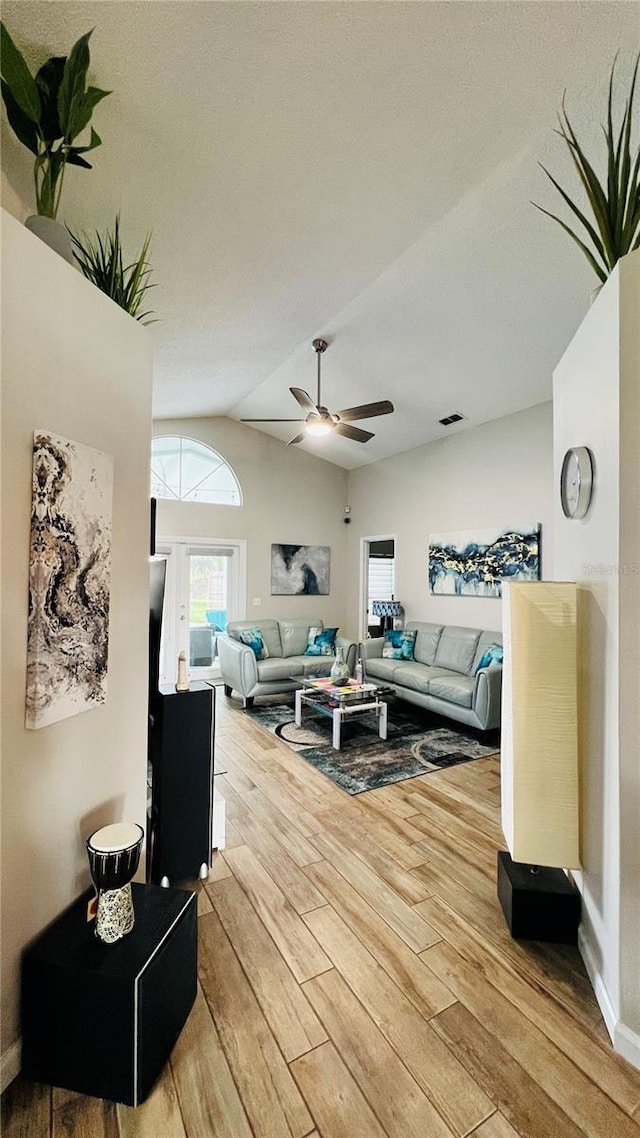living area with wood finished floors, ceiling fan, baseboards, and lofted ceiling