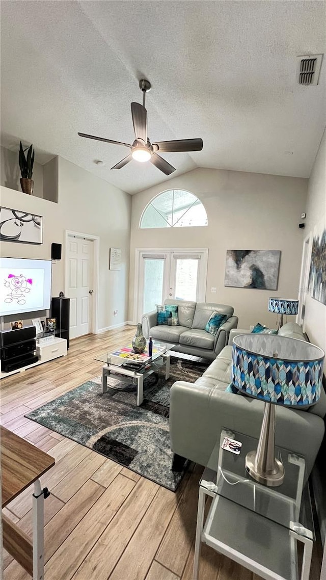 living room with ceiling fan, a textured ceiling, wood finished floors, and lofted ceiling