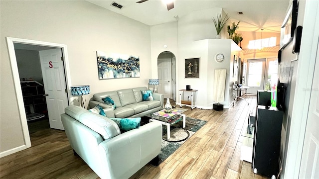 living area with ceiling fan, light wood-style flooring, arched walkways, visible vents, and a high ceiling
