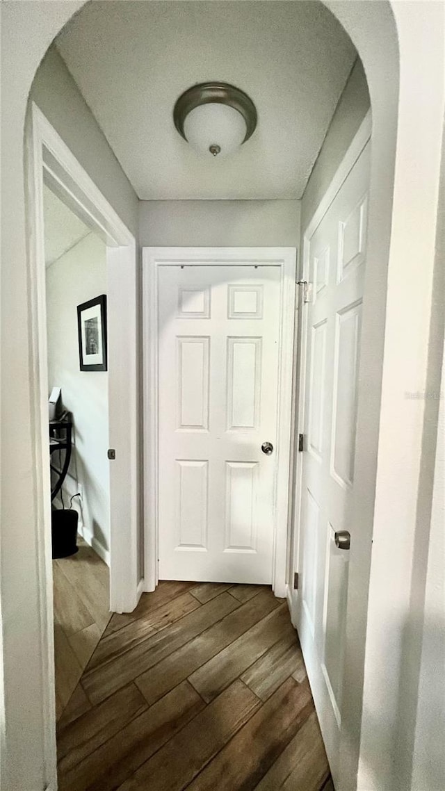 corridor featuring arched walkways and dark wood finished floors