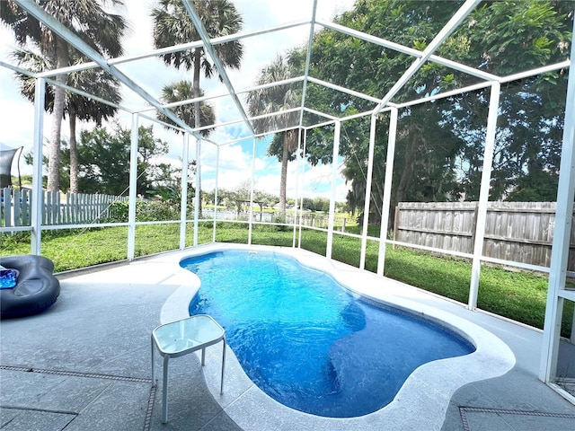 view of pool featuring a patio area, a lawn, a fenced backyard, glass enclosure, and a fenced in pool